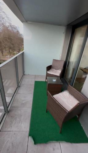 - un balcon avec 2 chaises et un sol vert dans l'établissement Agréable 3 pièces avec Parking proche Gare et Paris by immo Kit bnb, à La Courneuve