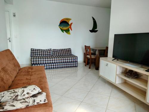 a living room with a couch and a flat screen tv at terraços do maitinga in Bertioga