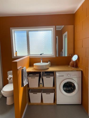 a bathroom with a washing machine and a sink at Suite Dreams in Tairua