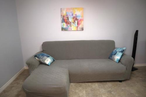 a couch with two pillows sitting under a painting at Calgary's Home Cinema Retreat in Calgary