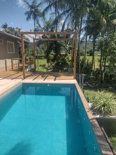 a swimming pool in a backyard with a pergola at Cantinho da nona Nova Trento SC in Nova Trento