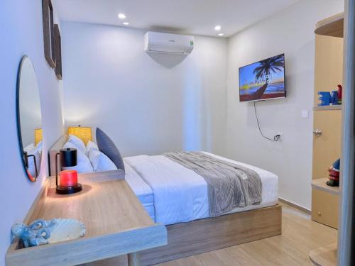 a bedroom with a bed and a table with a mirror at A cozy condotel in Bai Sau(1 bed and 1 sofa bed) in Vung Tau