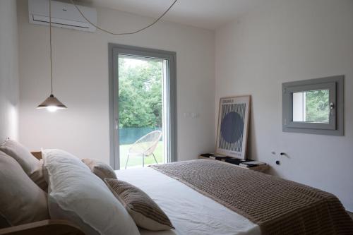 カステッリーナ・マリッティマにあるVilla La Leccina a Castellina Marittimaのベッドと窓のある白い寝室