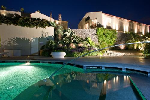a swimming pool in front of a house at night at Donna Carmela Resort & Lodges in Riposto