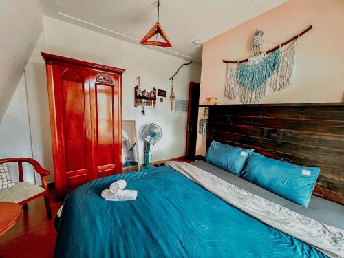 a bedroom with a blue bed with a wooden headboard at Oriana Dalat in Da Lat