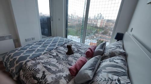 a dog sitting on a bed in front of a window at The Skyview Apartment near Media City & Old Trafford Stadium with Paid Gated Parking, 500Mbps Internet & Netflix in Manchester