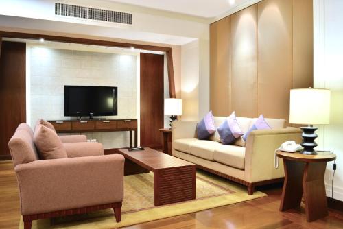 a living room with two chairs and a flat screen tv at Rama Gardens Hotel Bangkok in Bangkok