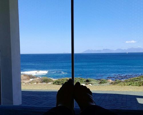 a person laying in front of a window looking at the ocean at ROMANZA APARTMeNT in De Kelders