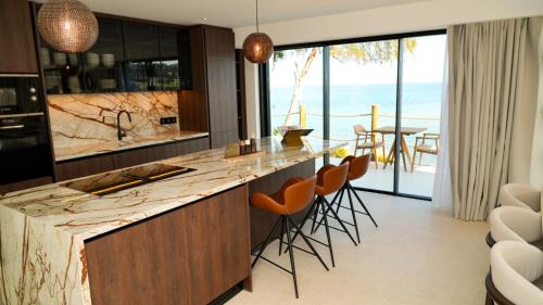 a kitchen with a counter with chairs and a view of the ocean at Sirena Bay Beach House and Luxury Suites in Protaras