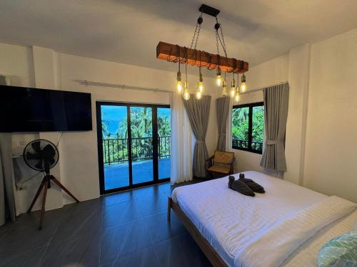 a bedroom with a bed and a television and windows at Tanouy Garden in Baan Khai