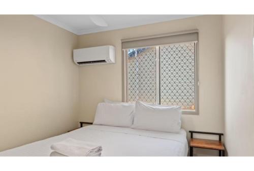 a bedroom with a white bed and a window at Discovery Parks - Port Hedland in Port Hedland