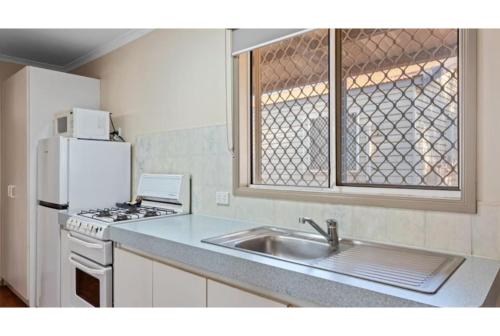 a kitchen with a sink and a stove and a refrigerator at Discovery Parks - Port Hedland in Port Hedland