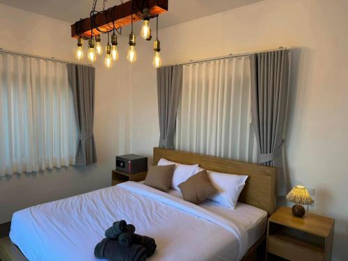 a bedroom with a bed with white sheets and windows at Tanouy Garden in Baan Khai