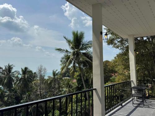 a porch with a chair and a palm tree at Tanouy Garden in Baan Khai