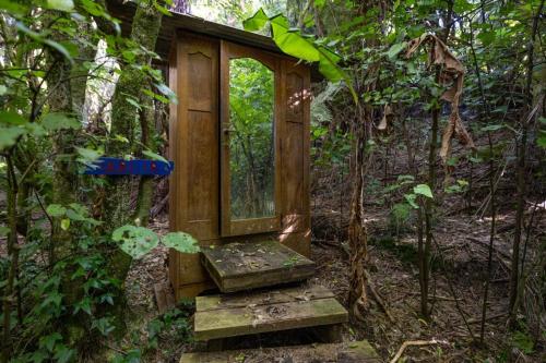 a wooden out house in the middle of a forest at The Land - Paradise to Share East Wing in Tata Beach