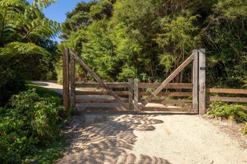 a wooden gate on a dirt road with trees at The Land - Paradise to Share East Wing in Tata Beach