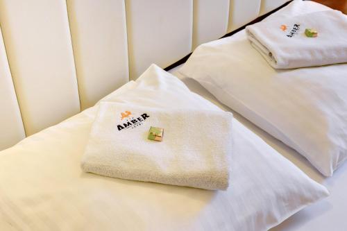 two white towels sitting on top of a bed at Amber Hotel in Gdańsk