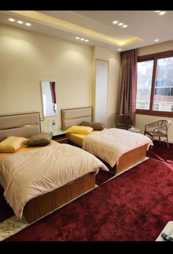 a bedroom with two beds and a red carpet at s5tar hotel rooms in front of Mansoura University in Mît Khamîs