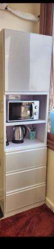 a white cabinet with a microwave in a kitchen at s5tar hotel rooms in front of Mansoura University in Mît Khamîs