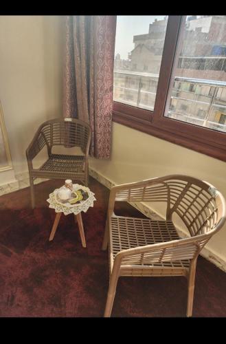 two chairs and a table in a room with a window at s5tar hotel rooms in front of Mansoura University in Mît Khamîs