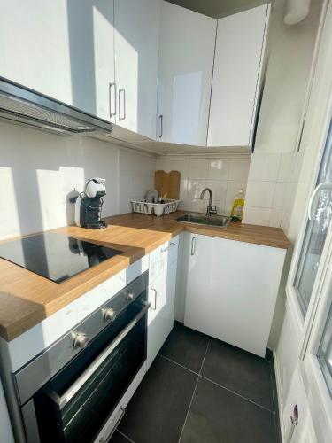 une cuisine avec des armoires blanches et un évier dans l'établissement F1 lumineux au cœur d'Argenteuil, à Argenteuil