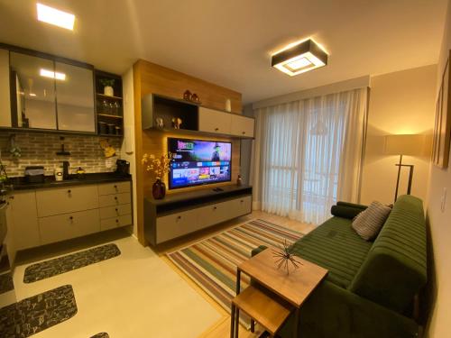 a living room with a green couch and a television at Loft Sou Mais Icaraí in Niterói