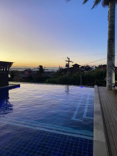 a swimming pool with a sunset in the background at Hotel Pousada Casacolina in Búzios