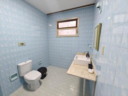 a blue bathroom with a toilet and a sink at Central House in Itajaí