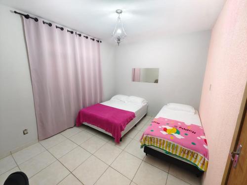 a room with two beds and a pink blanket at Central House in Itajaí