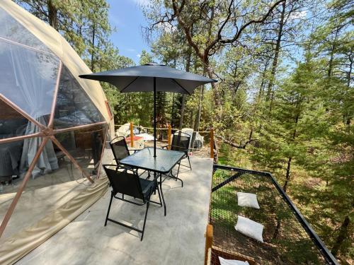 a patio with a table and chairs and an umbrella at Luahara Glamping Tapalpa - Domo Natural Experience in Tapalpa