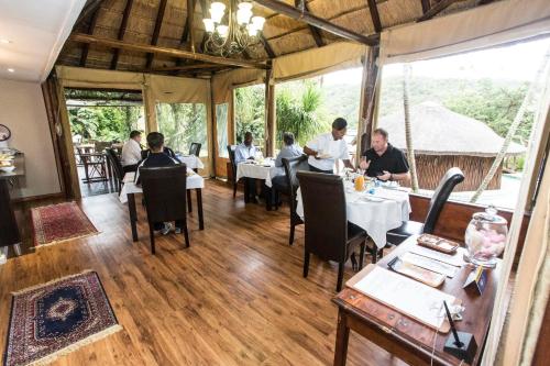 a group of people sitting at tables in a restaurant at Fish Eagle Manor in East London