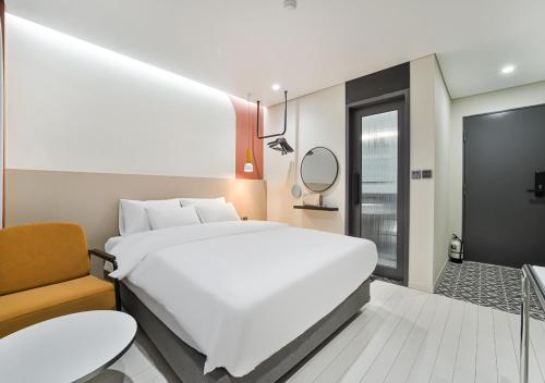 a bedroom with a large white bed and a chair at 호텔그랑파리 in Gwangju