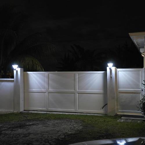 a white fence at night with lights on it at Villa Manakit in Petit-Bourg