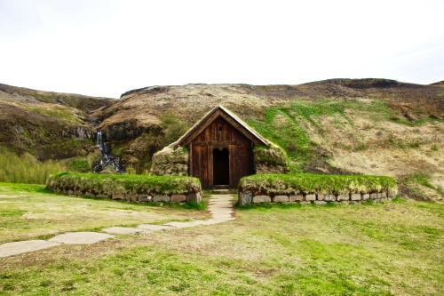 a small building in a field with a hill at Brún in Laugaras