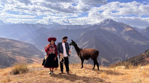 a man and woman standing next to a llama on a mountain at Sky Dome Peru in Cusco