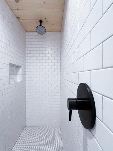 a white tiled bathroom with a black toilet paper dispenser at Piety Hill Cottages in Nevada City