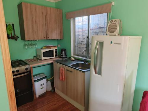 a small kitchen with a refrigerator and a sink at Cabaña YEYITA Playa Las Ventanas in Puchuncaví