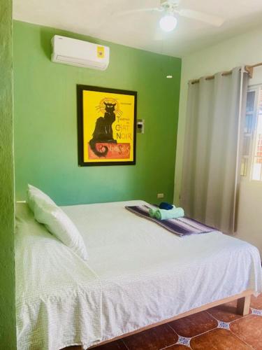 a green bedroom with a bed with a white blanket at Casa Kini en Cancún in Cancún