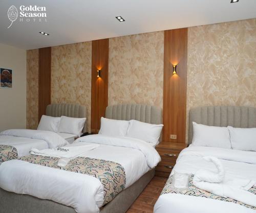 three beds in a hotel room with white sheets at Golden Season Hotel in Cairo
