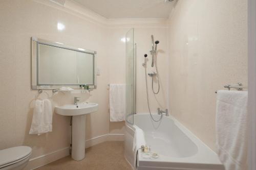 a bathroom with a sink and a tub and a toilet at Town House Rooms in Hastings