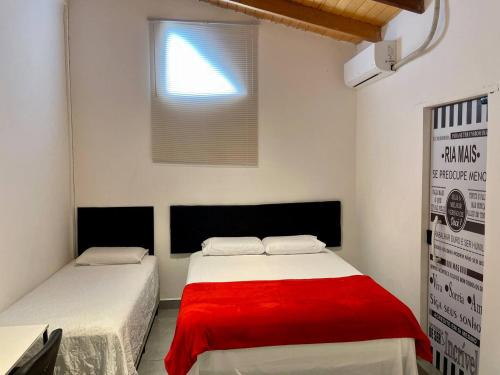 a bedroom with two beds with red sheets and a window at Unidades mobiliadas em condomínio in Lucas do Rio Verde