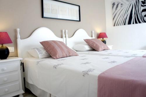 una camera da letto con un letto bianco con cuscini rosa e bianchi di Departamento Corriquia a Playa Blanca