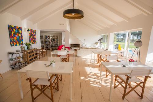 a dining room with white tables and chairs at Casas da Lupa in Zambujeira do Mar