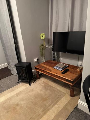 a living room with a wooden coffee table and a flat screen tv at 2 Guests - Free Parking - 6min to Derbion Centre in Derby