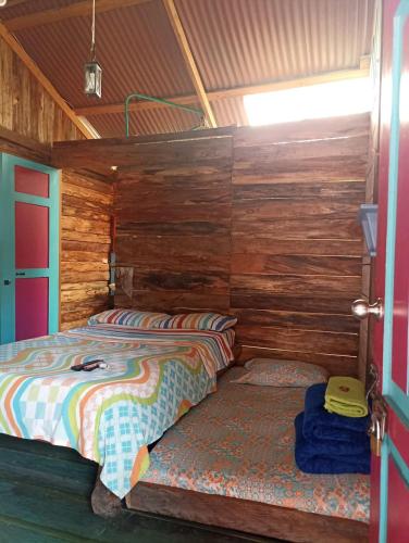 a bedroom with a bed in a wooden cabin at Hotel y Estadero Los Colores in Pajarito