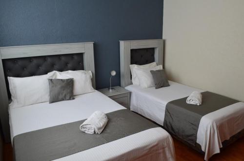 zwei Betten in einem Hotelzimmer mit weißen Handtüchern in der Unterkunft Casa Blue El place ideal for tu descanso in Puebla