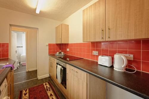 a kitchen with wooden cabinets and red tiles at Silver Bambu Liverpool Hideaway in Liverpool