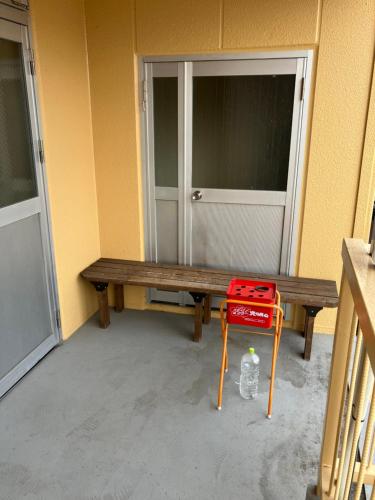 a wooden bench with a red stool in front of a door at Hotel 46 in Hashimoto
