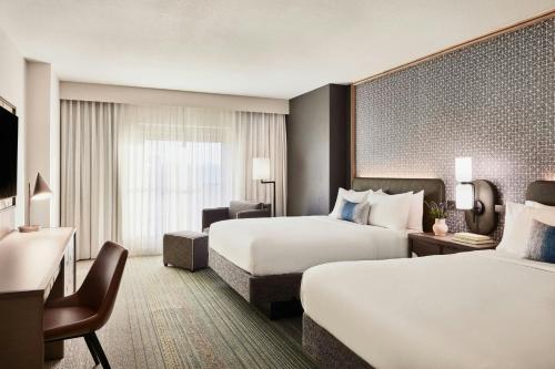 a hotel room with two beds and a desk at Renaissance Phoenix Glendale Hotel & Conference Center in Glendale