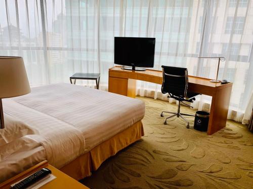a hotel room with a bed and a desk with a computer at Ascott Raffles City Beijing in Beijing